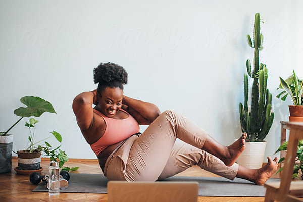 Woman smiling during a home workout with a laptop in front of her
