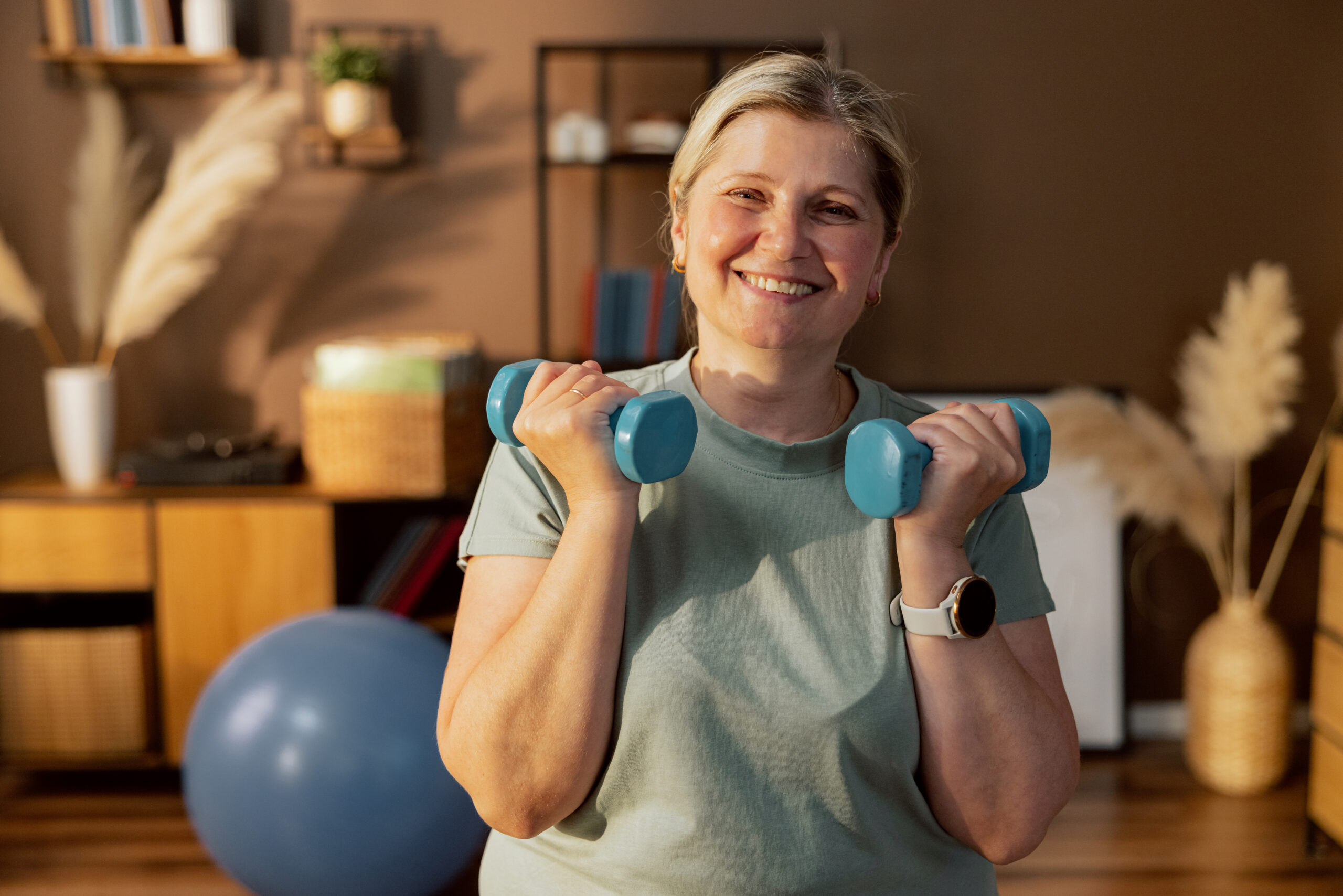 Smiling woman holding dumbbells at home